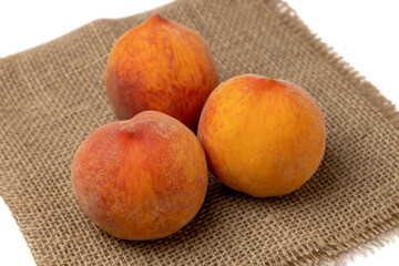 Peaches. Three ripe peaches on burlap isolated on a white background closeup.