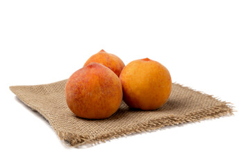 Peaches. Three sweet peaches on burlap isolated on a white background.