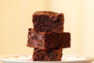 stack of three of square brownies slices in dark mood style, dark chocolate
