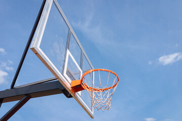 basketball board with basket hoop against blue sky.