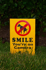 Germantown, MD, USA 06/24/2020: A lawn sign put up by a home owner to fend off dog keepers who allow their pets to poop in the front yard. The notice says: "smile you are on camera"