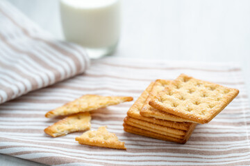 Fototapeta na wymiar sugar crackers on textured fabric against glass of milk.