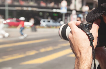 Photographer takes photographs with dslr camera in a city.