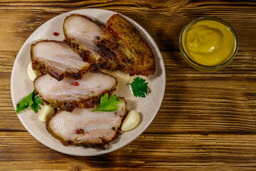 Baked pork belly in a plate on wooden table. Top view