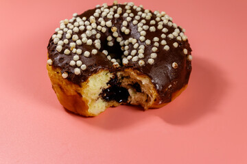Bitten tasty chocolate donut on a pink background