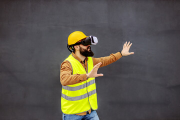 Young bearded constructor in working wear having virtual reality experience.