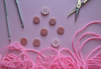 Stitching equipment including buttons needle and scissors on pink color background