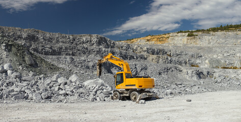 Hydraulic breaker breaks rocks in a quarry, panorama. Mining industry.