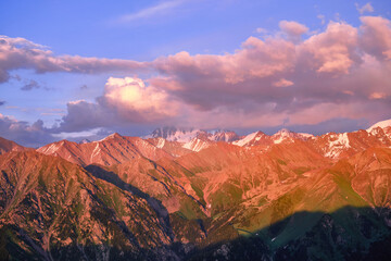 Fototapeta na wymiar Grandiose mountain valley with ridges of snowy peaks at sunset