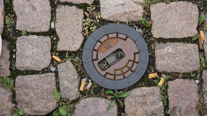 Manhole lid surrounded with cigarette buds