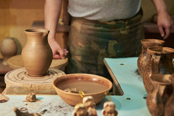 Fototapeta na wymiar Process of making clay pot on a potter's wheel in workshop. Potter at work