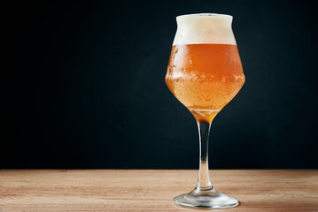 Glass of cold beer with foam on dark background. Craft beer, studio shot