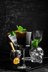 Cocktail with cola. Rum with cola and mint in a beautiful glass. On a black stone background. Menu bar. Alcohol.