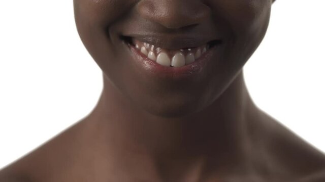 Lower face portrait of young african woman, sticking out her tongue and smiling wide on white background