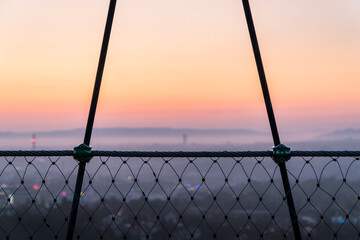 A wire fence framing the town of stuttgart during dawn.