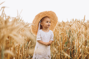 pretty cute baby girl with a beautiful smile wearing summer straw hat in a walk in the  wheat fields. selective focus. family, people concept