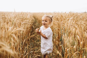 pretty cute baby girl with a beautiful smile wearing summer straw hat in a walk in the  wheat fields. selective focus. family, people concept