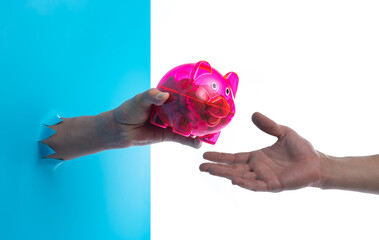 Hand holding a red piggy bank through the torn blue plastic background