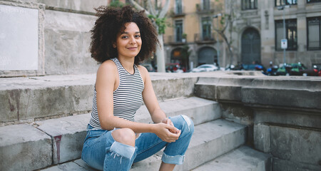 Satisfied young woman sitting on steps in Barcelona