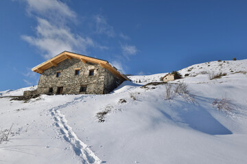 traditional alpine chalet at the top of snowy mountain under blue sky