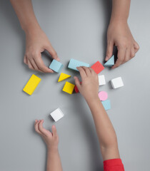 Concept of development and training of a child at home during the pandemic of coronavirus and COVID-19, Mother and child's hands playing with colorful wooden bricks