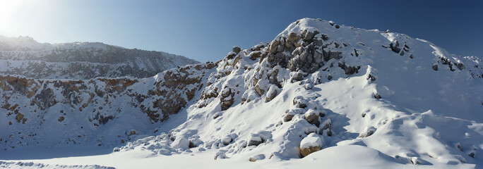 Panorama of the relief in a stone quarry covered with snow in a winter sunny day.