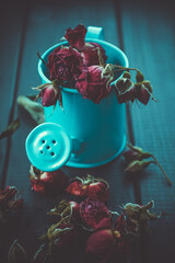 Blue watering can with red roses on a wooden table. - 361481146