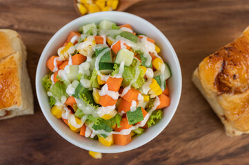 Cucumber salad, corn, carrot and lettuce in a white cup.