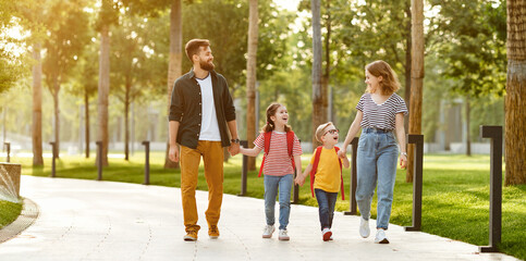 Happy family walking to school in park.