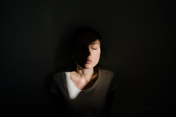 Girl sitting alone in sunlight pocket in dark room. mental health concept