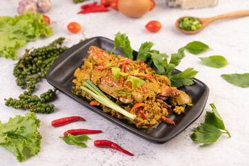 Crab stir-fried curry powder on a black plate on the cement floor.