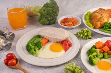 Breakfast consisting of bread, fried eggs, broccoli, carrots, tomatoes and lettuce on a white plate.
