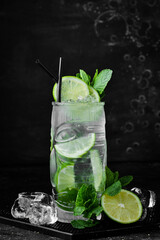 Mojito cocktail with mint and lime. Summer tonic cocktail. on a black stone background. Menu bar....