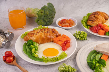 Breakfast consisting of bread, fried eggs, broccoli, carrots, tomatoes and lettuce on a white plate.