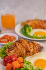 Breakfast consisting of bread, fried eggs, broccoli, carrots, tomatoes and lettuce on a white plate.