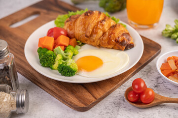 Breakfast consisting of bread, fried eggs, broccoli, carrots, tomatoes and lettuce on a white plate.