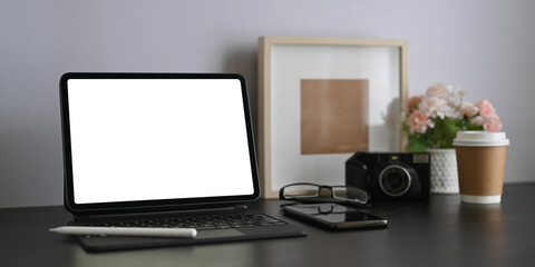 A workspace is surrounding by white blank screen computer tablet and personal equipment.