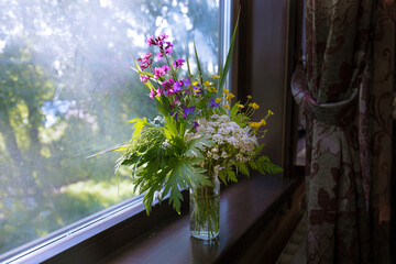 beautiful summer bouquet of wild flowers on the windowsill at home