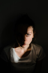 Girl sitting alone in sunlight pocket in dark room. mental health concept