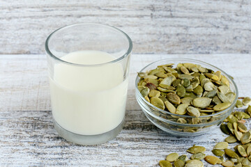 Alternative dairy pumpkin seeds milk in small drinking glass with ingridients