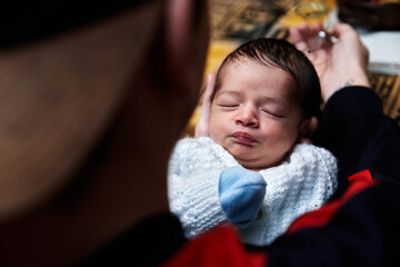 beautiful and adorable newborn baby held by its father in his hands and he caresses it while the...