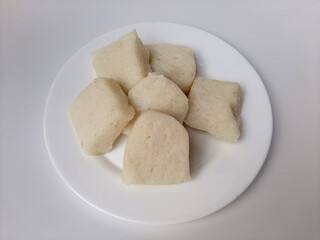 Jadah ketan, is a traditional snack from Indonesia. Made from sticky rice and grated coconut. Commonly served as tea time snack. On a white plate, isolated in white background