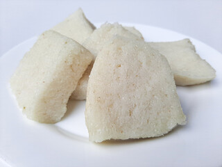 Jadah ketan, is a traditional snack from Indonesia. Made from sticky rice and grated coconut. Commonly served as tea time snack. On a white plate, isolated in white background