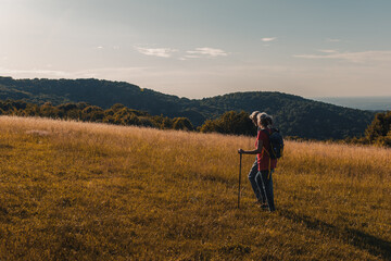 Active senior couple hiking in nature with backpacks, enjoying their adventure at sunset.