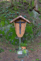 A pillar with a crucifix on a mountainside trail.