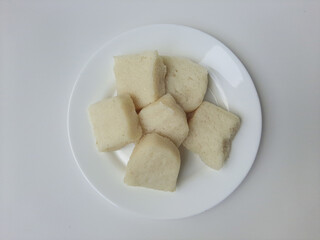 Jadah ketan, is a traditional snack from Indonesia. Made from sticky rice and grated coconut. Commonly served as tea time snack. On a white plate, isolated in white background
