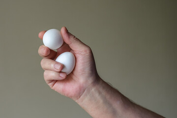Brutal male hand holding two fresh white chicken eggs