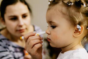 mom and daughter, mom as a makeup artist draws freckles on the face of a child. Home games and fun in a happy family