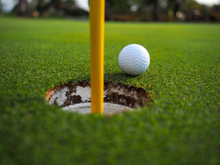 White golf balls that are going into the hole.