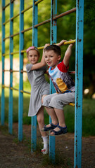 Fototapeta premium Cute little girl and boy hanging together on crossbar of sport staircase